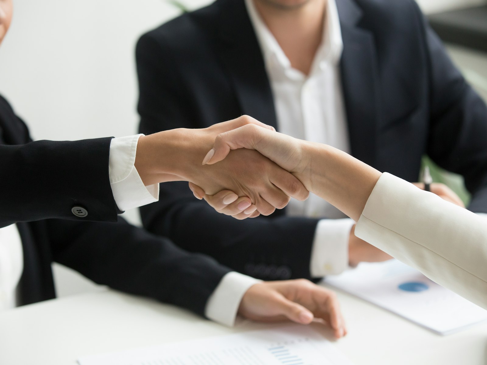 Poignée de main entre deux professionnels, au-dessus d’un bureau
